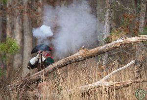Patriots fires from behind log branch